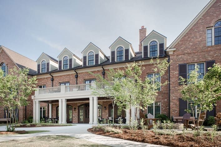 The Barnsley Inn, a two-story brick building with arched windows, dormers, and a covered entrance, surrounded by landscaped greenery and trees.